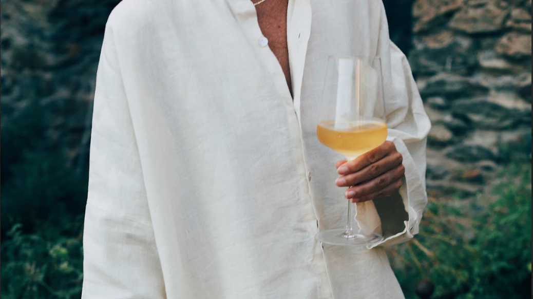 Close-up of a hand holding gluten free white wine in a stemmed glass.